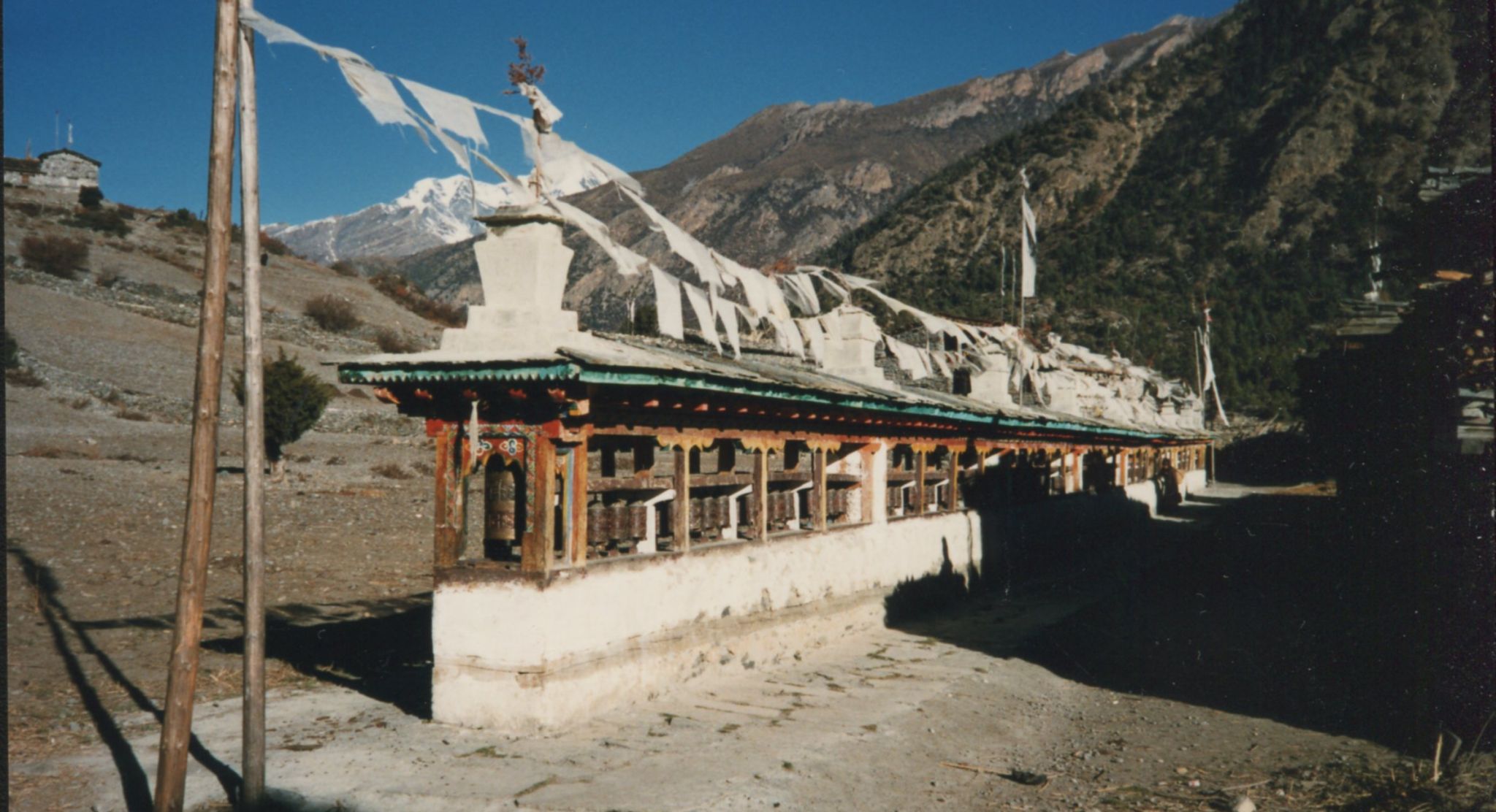 Mani Wall ( Buddhist shrine ) with Prayer Flags and Prayer Wheels